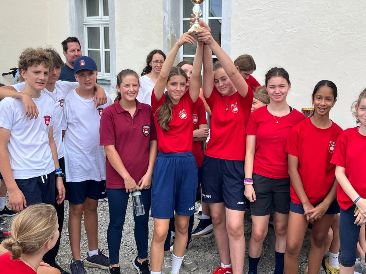 Jubelnde Schülerinnen und Schüler der Unterstufe mit Pokal beim Sporttag